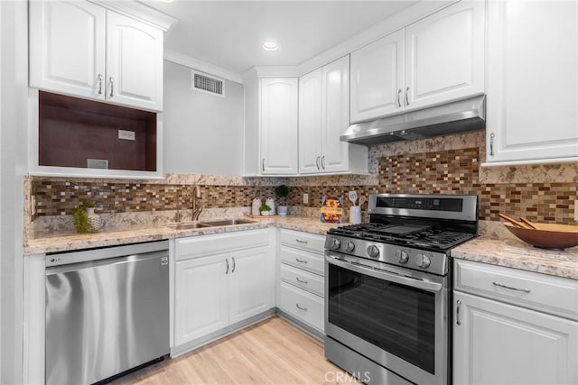 kitchen with visible vents, under cabinet range hood, appliances with stainless steel finishes, white cabinetry, and a sink