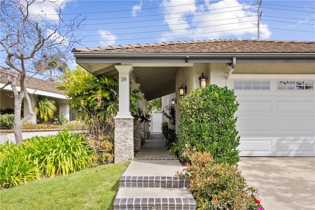 view of exterior entry with a porch, stucco siding, an attached garage, and driveway