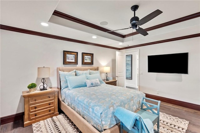 bedroom with a tray ceiling, baseboards, and wood finished floors