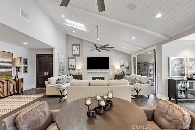 living room with visible vents, wood finished floors, beamed ceiling, and ceiling fan