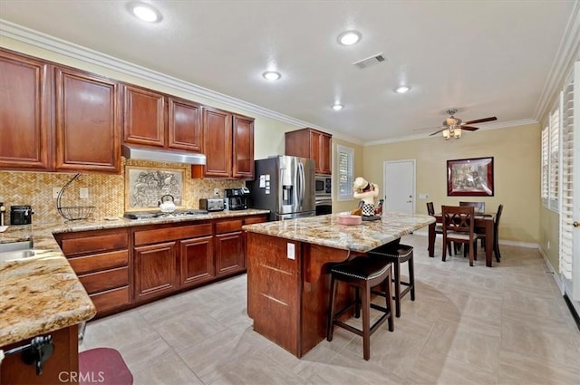 kitchen featuring a breakfast bar area, visible vents, a kitchen island, stainless steel appliances, and under cabinet range hood