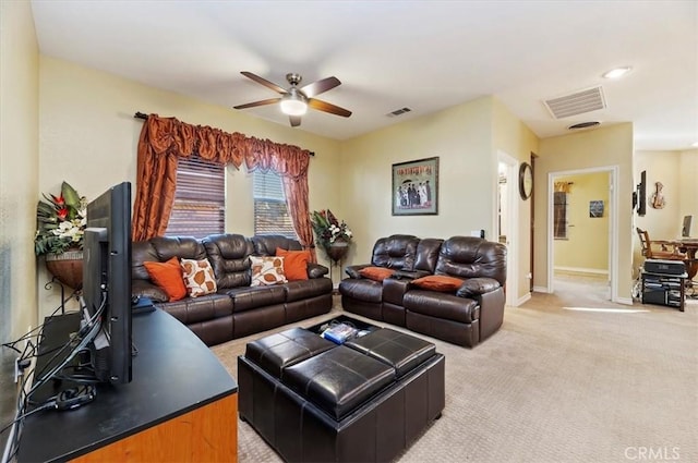 living area featuring light carpet, visible vents, baseboards, and ceiling fan