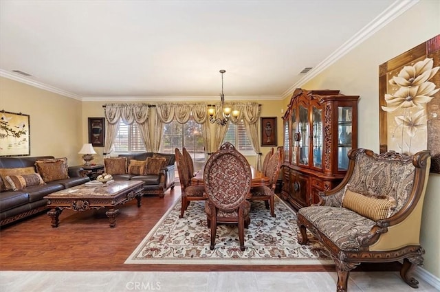 dining room featuring a chandelier, visible vents, crown molding, and wood finished floors