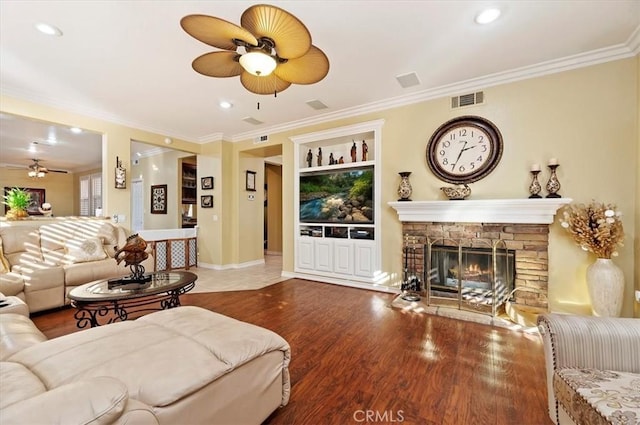 living area featuring visible vents, ornamental molding, a ceiling fan, and wood finished floors