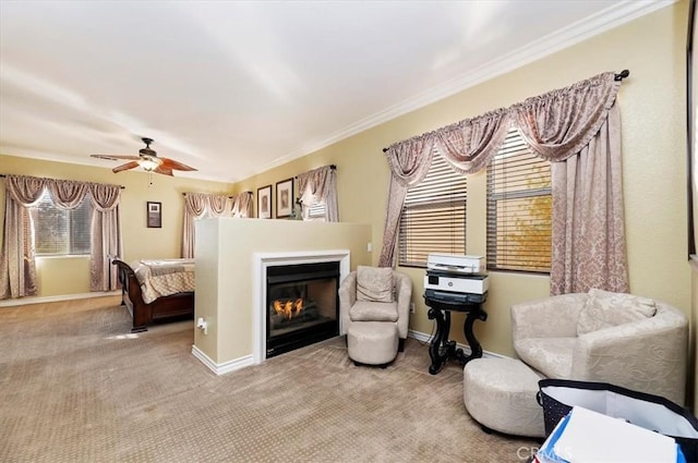 sitting room featuring baseboards, ceiling fan, a glass covered fireplace, crown molding, and carpet flooring