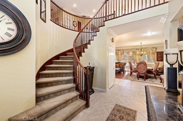 staircase featuring crown molding, baseboards, a towering ceiling, and a chandelier