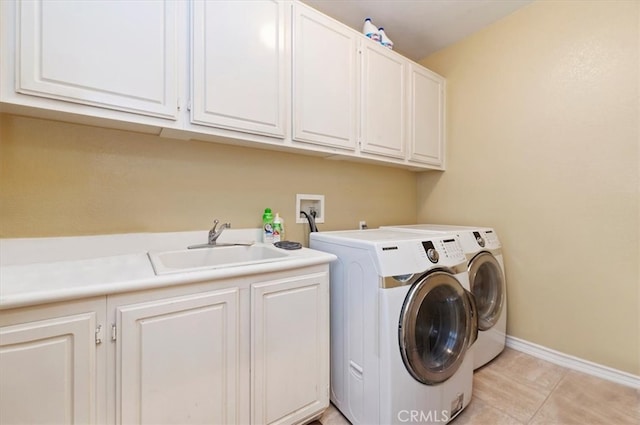 laundry area featuring baseboards, washing machine and dryer, light tile patterned floors, cabinet space, and a sink