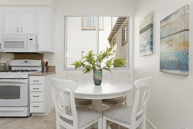 kitchen featuring white cabinetry, white appliances, and baseboards