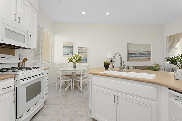 kitchen with white appliances, white cabinets, light countertops, and a sink