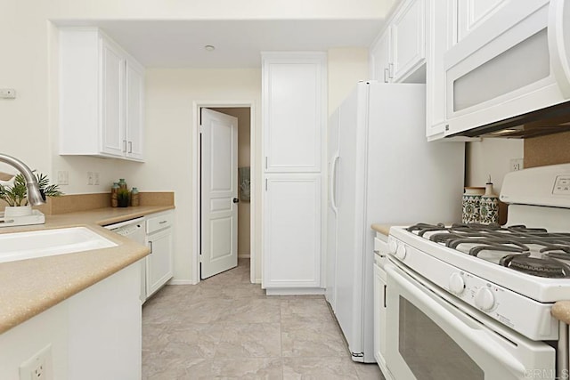 kitchen with a sink, white appliances, light countertops, and white cabinetry