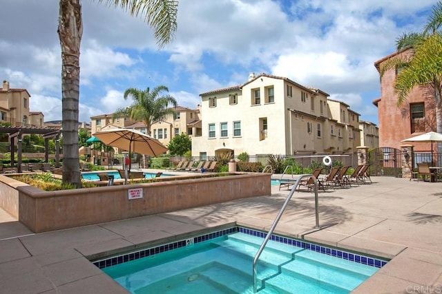 pool with a patio area, a residential view, a community hot tub, and fence