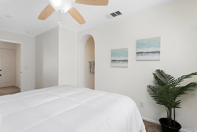 bedroom featuring visible vents, a ceiling fan, carpet floors, arched walkways, and baseboards