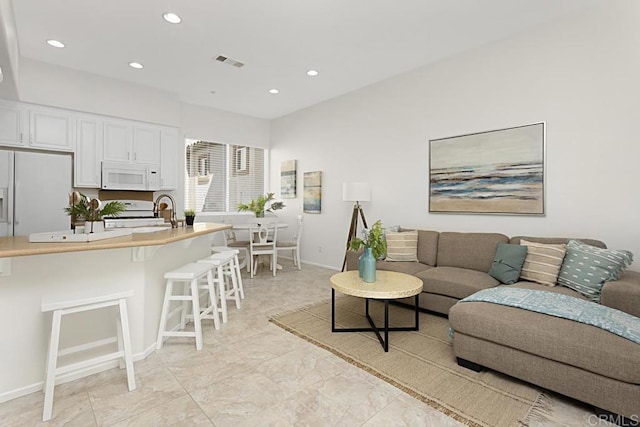 living room with recessed lighting, visible vents, and baseboards