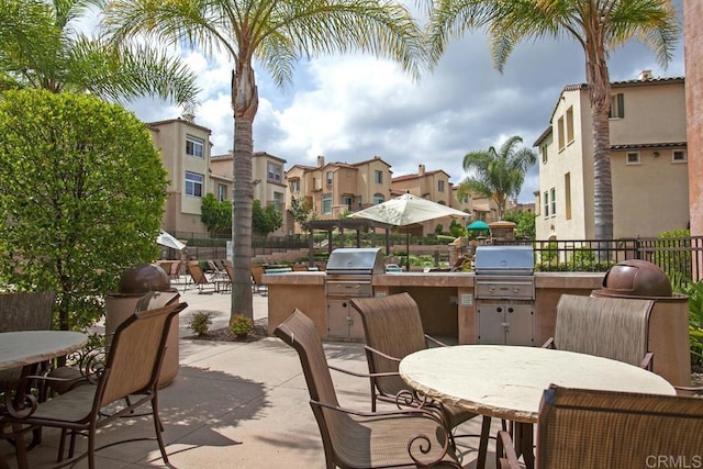 view of patio with area for grilling, exterior kitchen, outdoor dining space, and fence