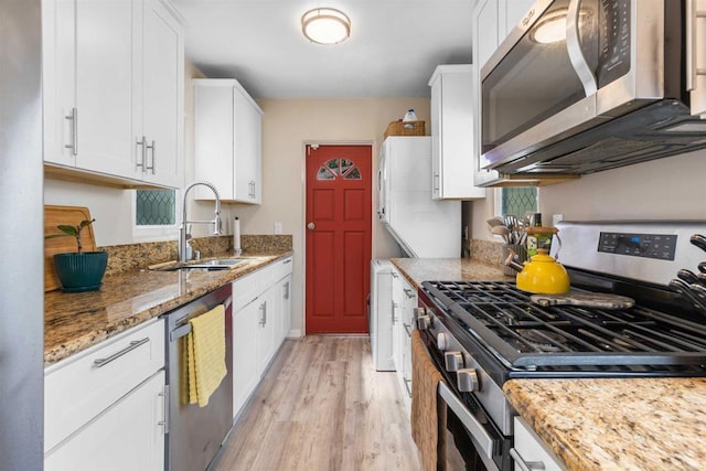 kitchen featuring a sink, stainless steel appliances, light wood-type flooring, and white cabinetry