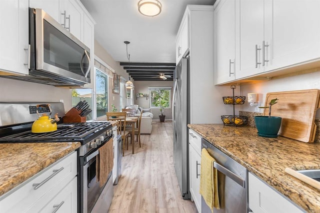 kitchen featuring light stone countertops, light wood-style flooring, stainless steel appliances, hanging light fixtures, and white cabinetry