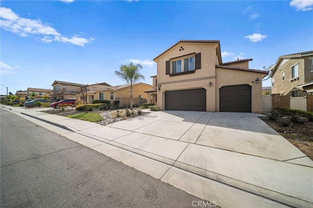 mediterranean / spanish house with fence, driveway, stucco siding, a garage, and a tile roof