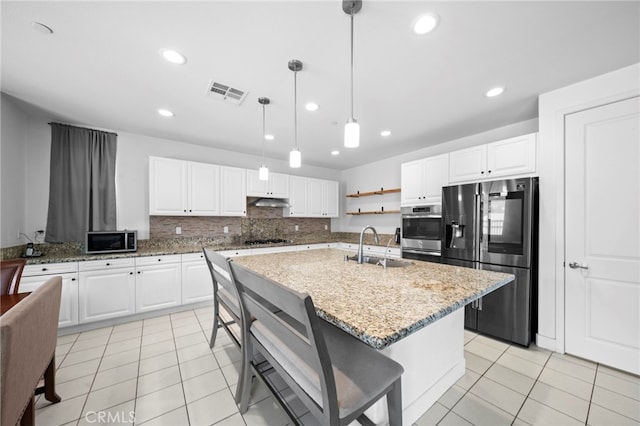 kitchen with visible vents, light stone countertops, appliances with stainless steel finishes, light tile patterned flooring, and a sink