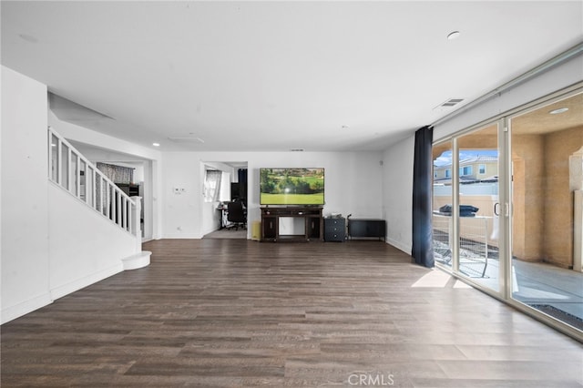 unfurnished living room with stairway, visible vents, and wood finished floors