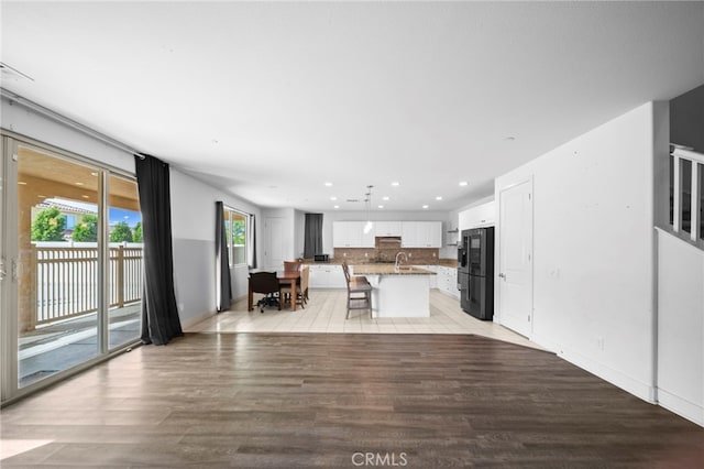 unfurnished living room with recessed lighting, light wood-type flooring, baseboards, and a sink