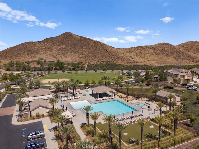 community pool with a patio area, fence, and a mountain view