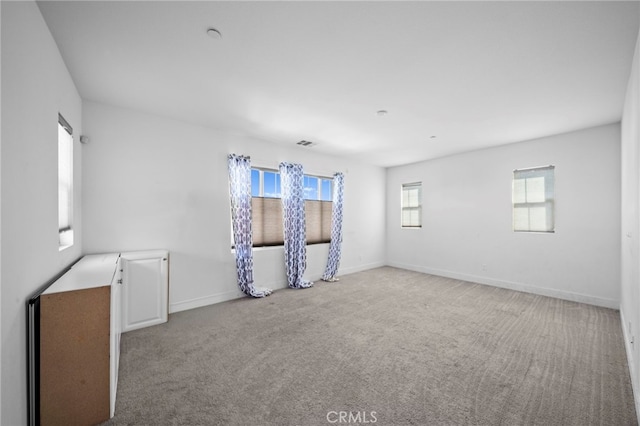 carpeted empty room with visible vents and baseboards