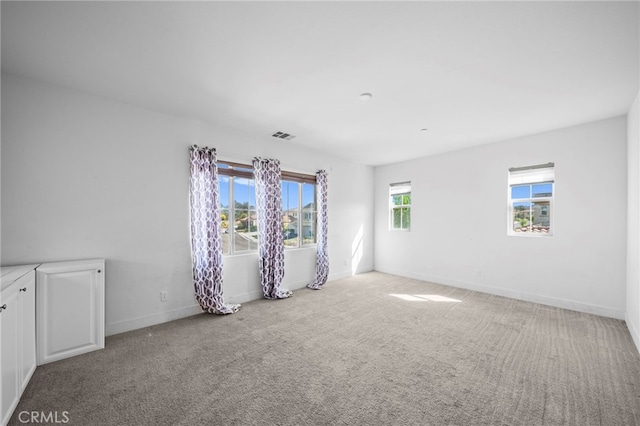 empty room with visible vents, carpet, and baseboards