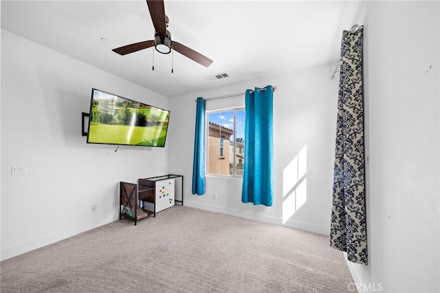 carpeted spare room with baseboards, visible vents, and ceiling fan