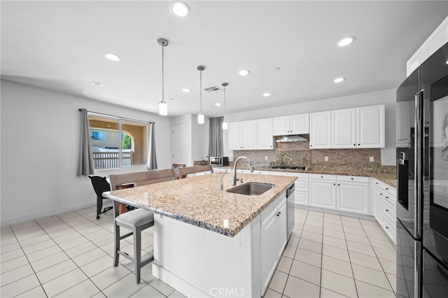 kitchen with tasteful backsplash, under cabinet range hood, a breakfast bar area, gas cooktop, and a sink