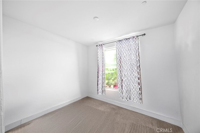 unfurnished room with carpet flooring and baseboards