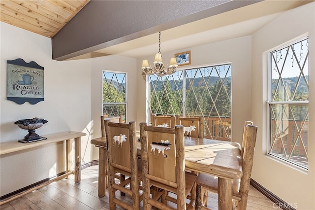 dining area featuring an inviting chandelier, light wood-style flooring, baseboards, and lofted ceiling