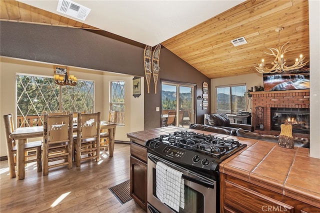 kitchen with tile countertops, visible vents, stainless steel gas stove, and a chandelier