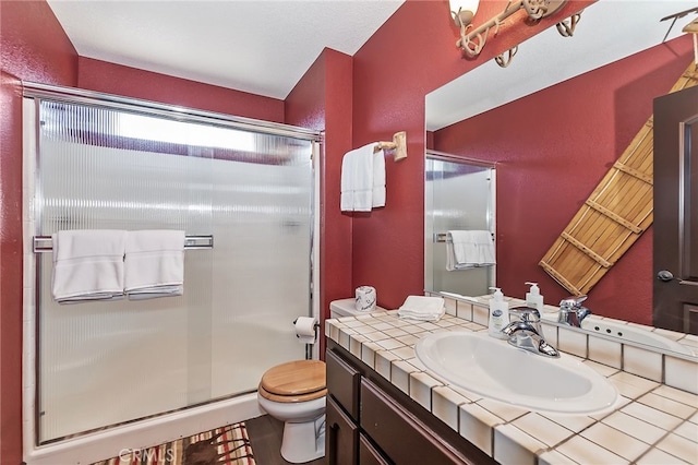 full bath featuring a shower stall, toilet, vanity, and a textured wall