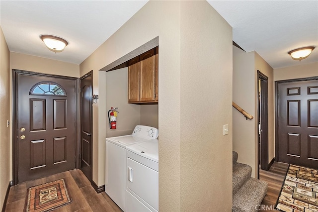 washroom featuring cabinet space, dark wood-style floors, and washing machine and clothes dryer