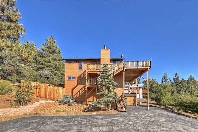 back of property with a deck, stairway, fence, and a chimney