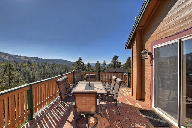 wooden terrace with outdoor dining area and a forest view