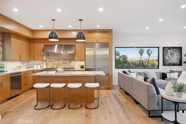 kitchen featuring under cabinet range hood, stainless steel appliances, light wood-type flooring, and a kitchen island