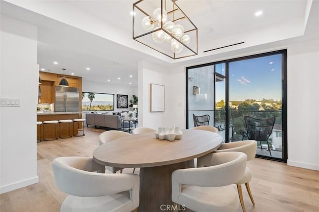 dining space with a raised ceiling, recessed lighting, light wood-style floors, baseboards, and a chandelier