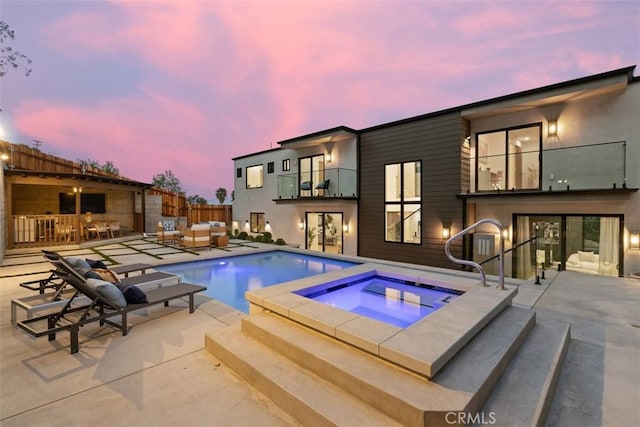 pool at dusk with a patio, fence, outdoor lounge area, a fenced in pool, and an in ground hot tub