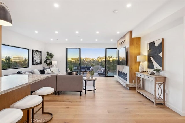 living area featuring recessed lighting, light wood-type flooring, baseboards, and a fireplace