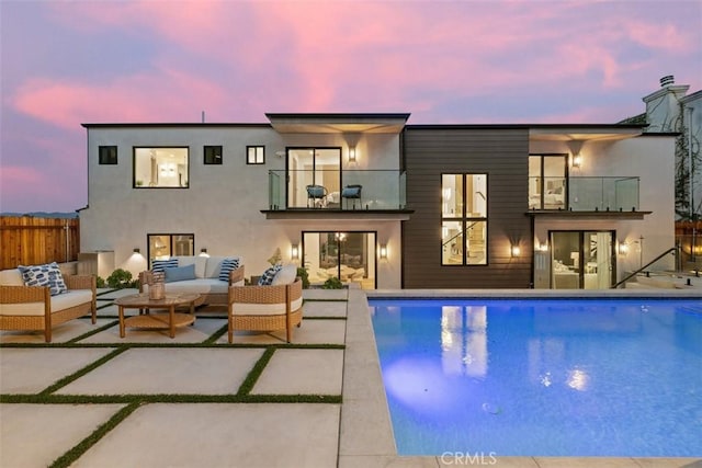 back of house with fence, stucco siding, an outdoor hangout area, a balcony, and a patio area