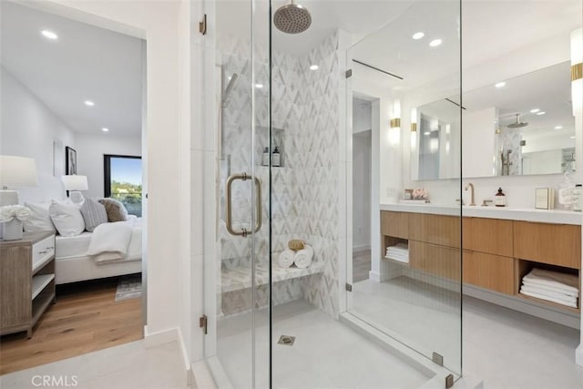 ensuite bathroom featuring recessed lighting, a stall shower, and vanity