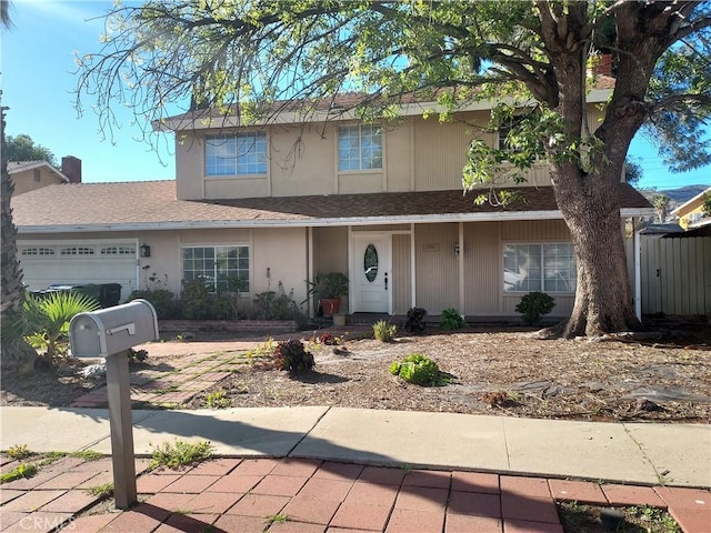 traditional home with stucco siding, a shingled roof, and a garage