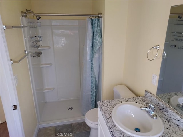 bathroom featuring vanity, a shower stall, and toilet