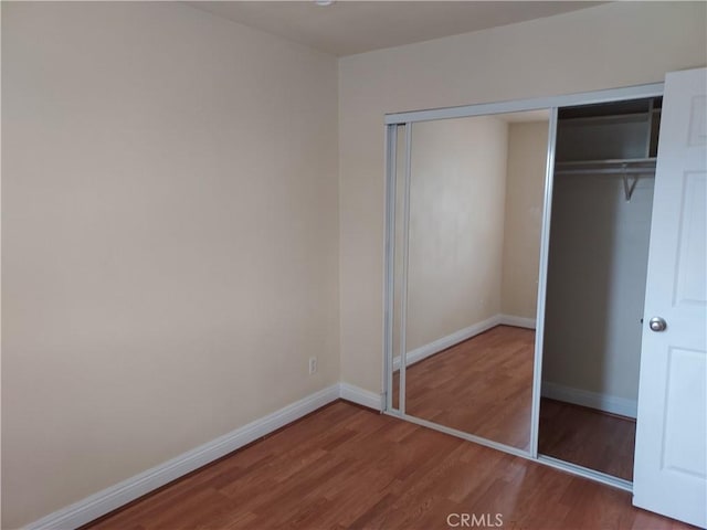 unfurnished bedroom featuring baseboards, a closet, and wood finished floors