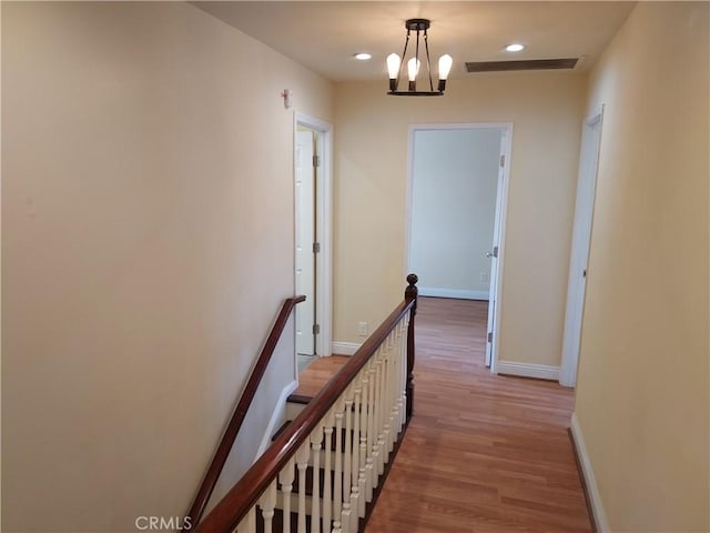 corridor featuring recessed lighting, baseboards, an upstairs landing, and wood finished floors