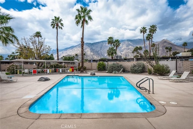 community pool featuring a mountain view, a patio, and fence