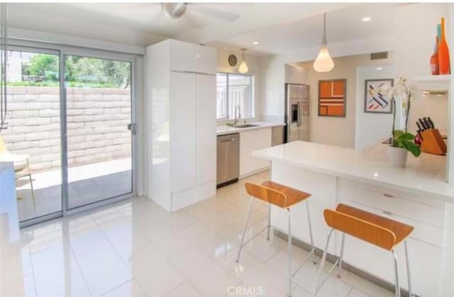 kitchen with a sink, stainless steel appliances, light countertops, white cabinets, and modern cabinets