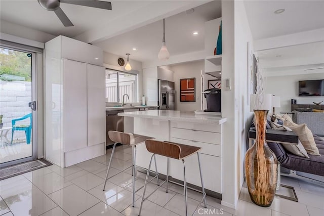 kitchen with open floor plan, a kitchen bar, appliances with stainless steel finishes, white cabinets, and modern cabinets