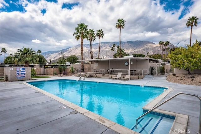 community pool featuring a patio, fence, and a mountain view